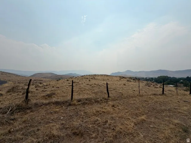 Expansive hillside lot featuring natural vegetation and distant mountain ranges