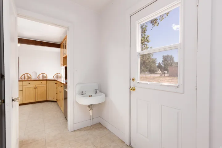 White paneled exterior door with glass inserts, wall-mounted utility sink, and tile flooring