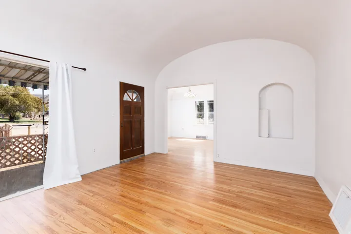 Arched doorways, hardwood flooring, a recessed wall niche, and an exterior door with a decorative glass insert