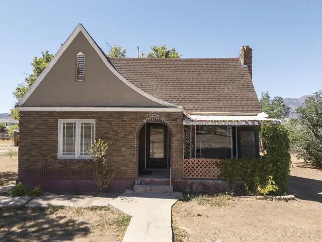 Brick exterior with a gabled roofline, decorative window grilles, a covered porch, and a concrete pathway