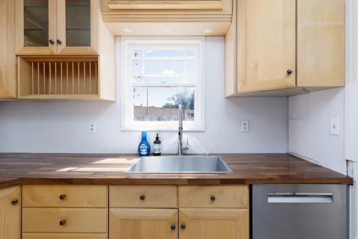 Wood-finish countertops with an undermount stainless steel sink and a stainless steel dishwasher