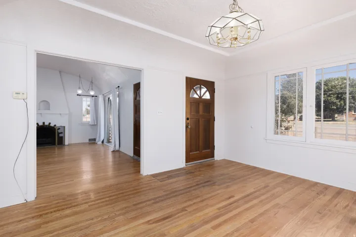 Wood-finish flooring throughout, solid wood entry door with arched lites, dual pane windows, and a decorative ceiling fixture