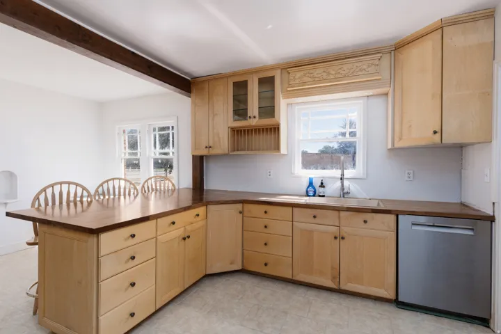 Kitchen featuring natural wood cabinetry, wood-finish countertops, stainless steel dishwasher, and a window above the sink