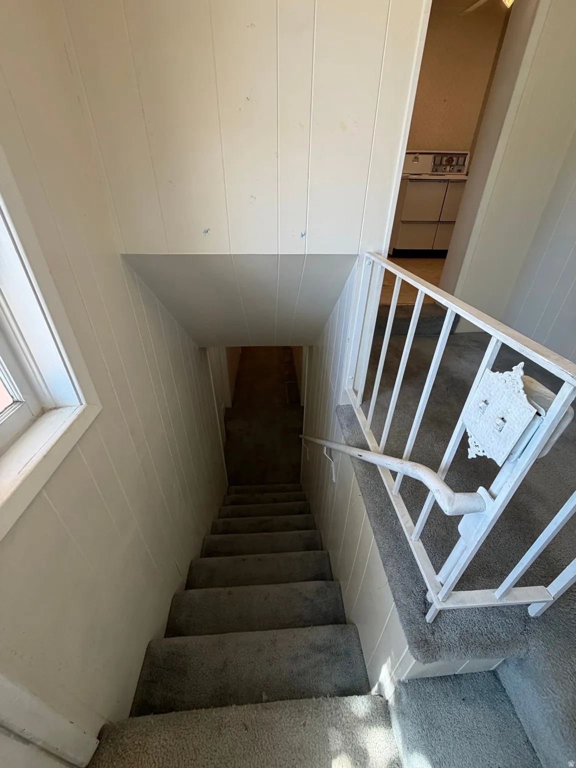 Carpeted staircase with white paneled walls and a white metal railing