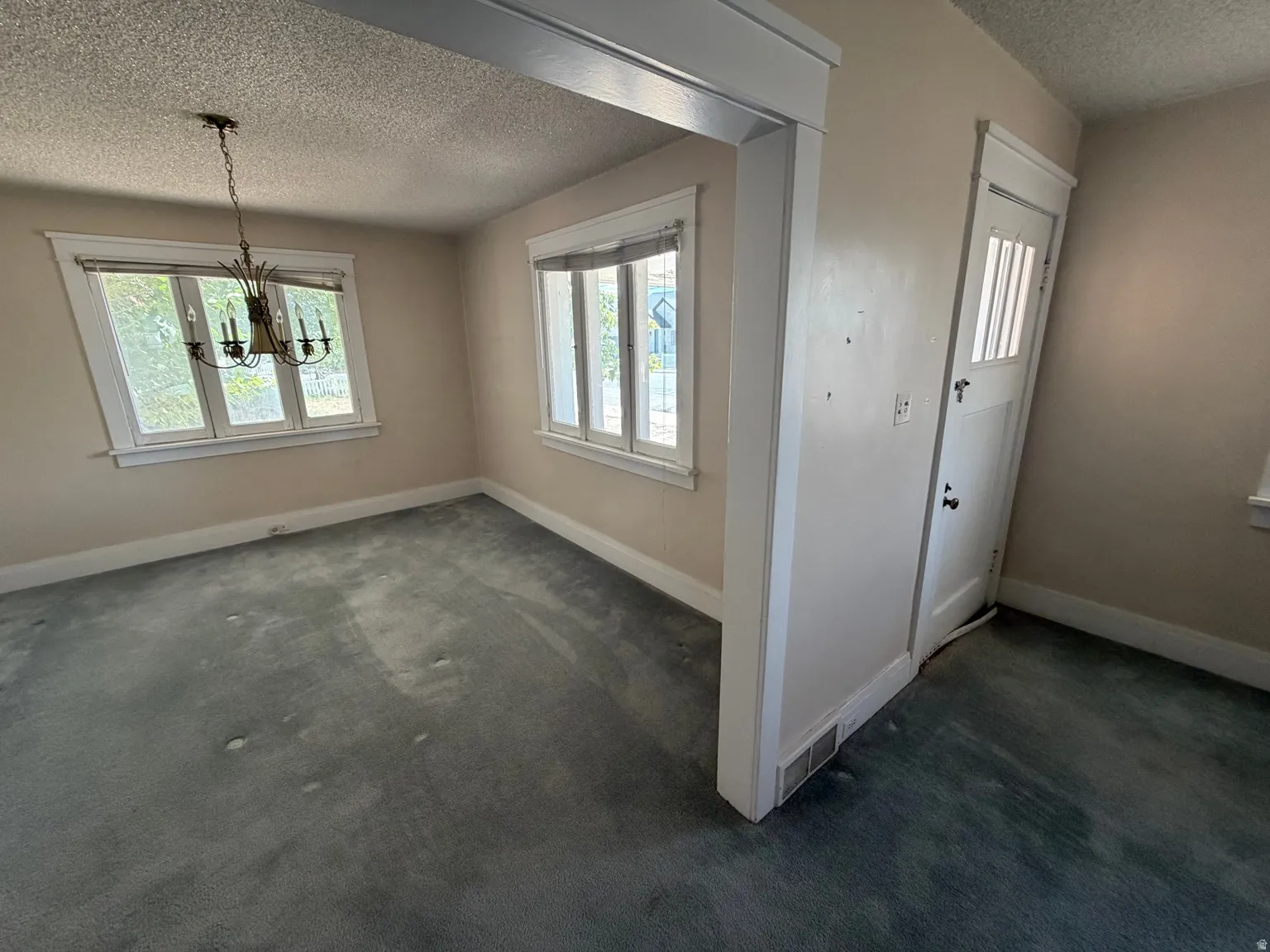 Two windows with white trim, a decorative chandelier, and a white paneled door