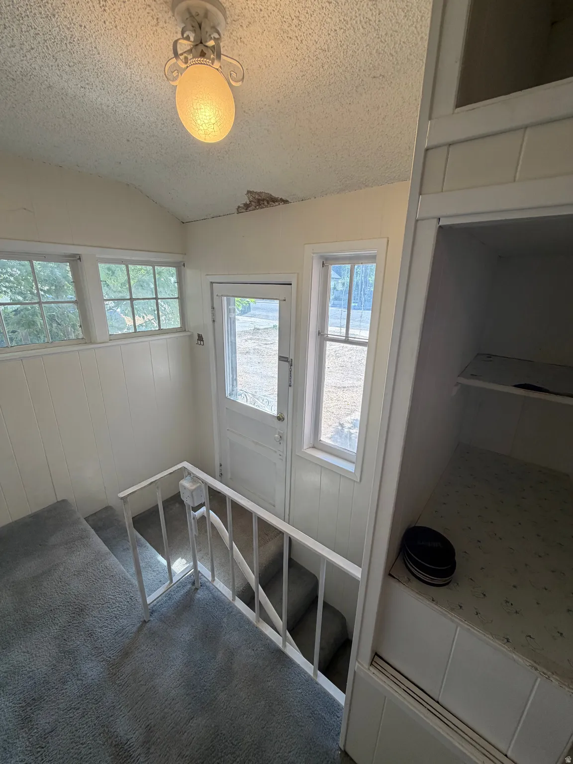 Built-in shelving, white beadboard paneling, white trim windows, white paneled door, and a flush-mount ceiling light fixture