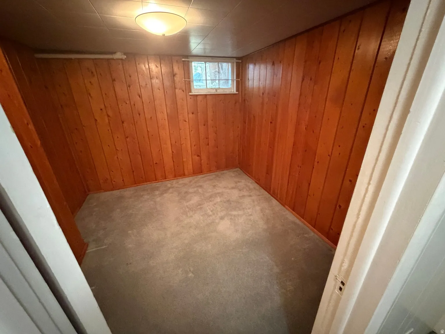 Wood paneling accents a bedroom with a window and ceiling-mounted light fixture