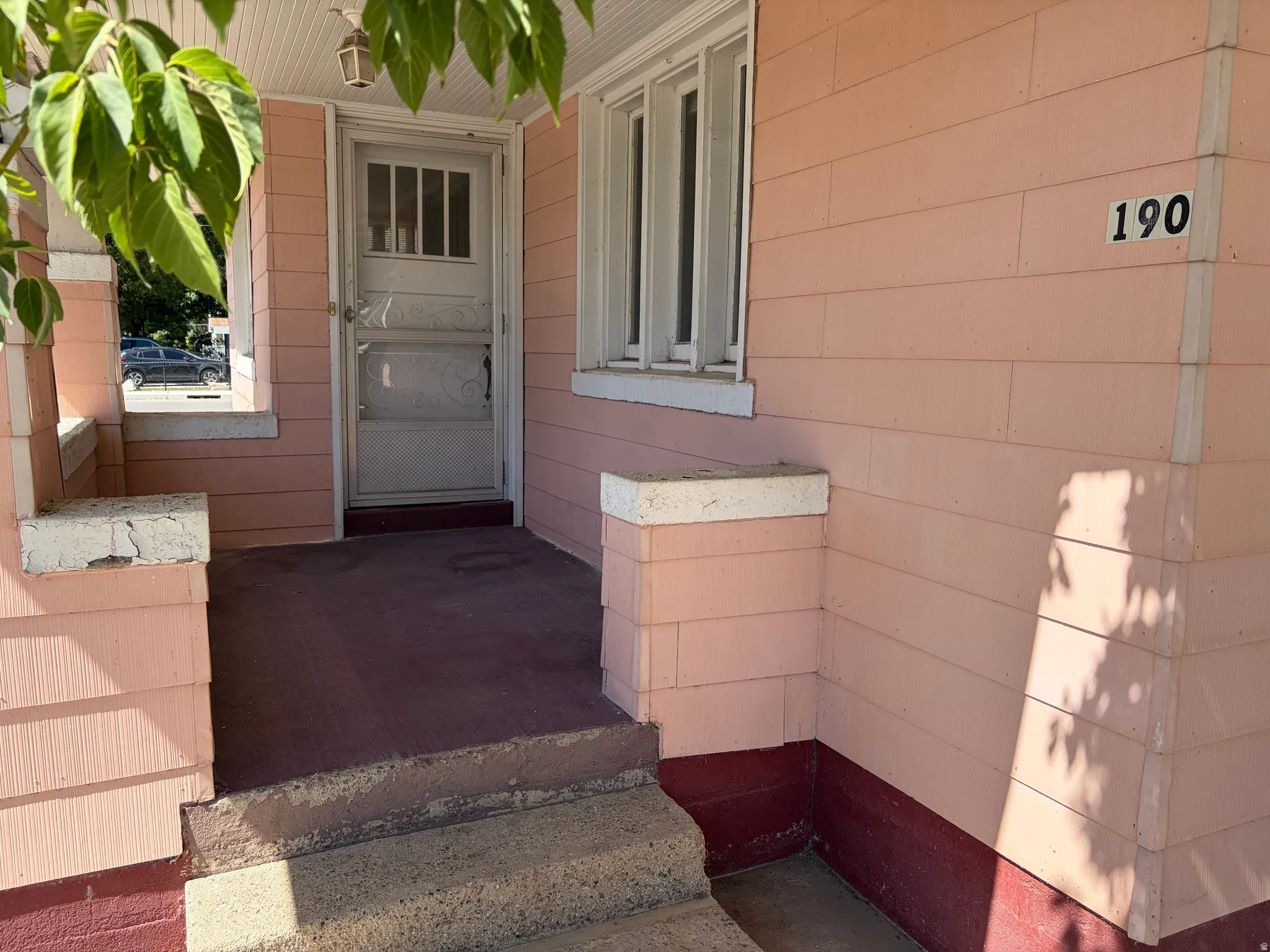 Front entry with concrete porch, concrete steps, and a white storm door
