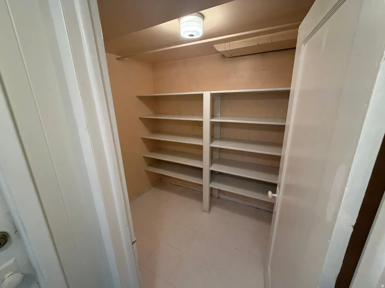 Built-in shelving with multiple levels, overhead lighting, and tile flooring