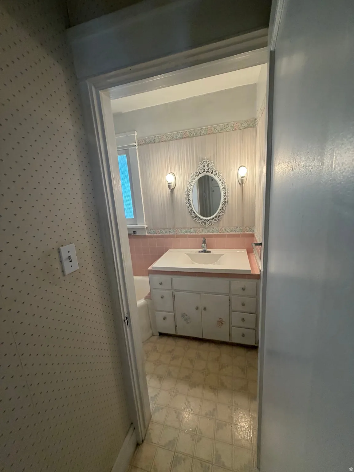 Bathroom featuring a built-in vanity with an integrated sink, wall-mounted sconces, and an ornamental mirror