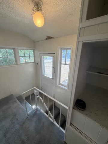 Built-in shelving, white beadboard paneling, white trim windows, white paneled door, and a flush-mount ceiling light fixture