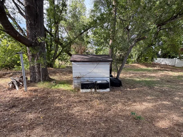 Backyard with shed, shade trees and stream in back