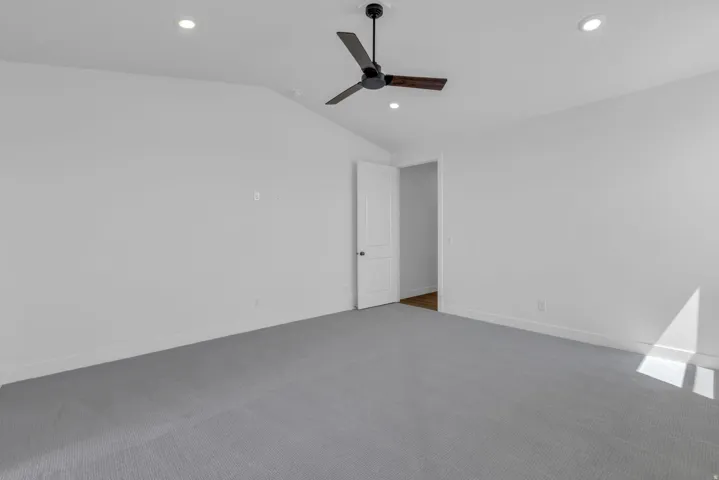 View from opposite side of primary bedroom.  Vaulted ceiling and ceiling fan.