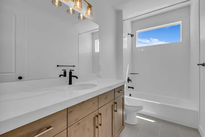 Secondary bathroom with wood cabinetry, Quartz countertops, upgraded black hardware, window for natural light