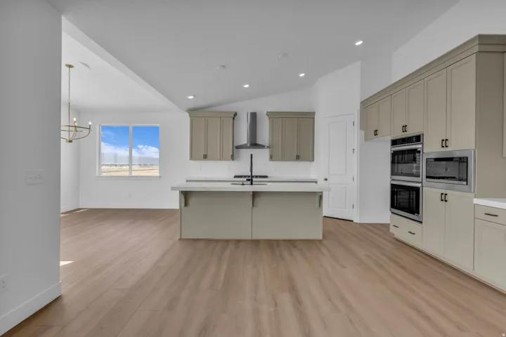 View of kitchen with vaulted ceilings,  double wall ovens and gourmet appliances, cooktop, dishwasher, microwave and large sink with upgraded hardware.