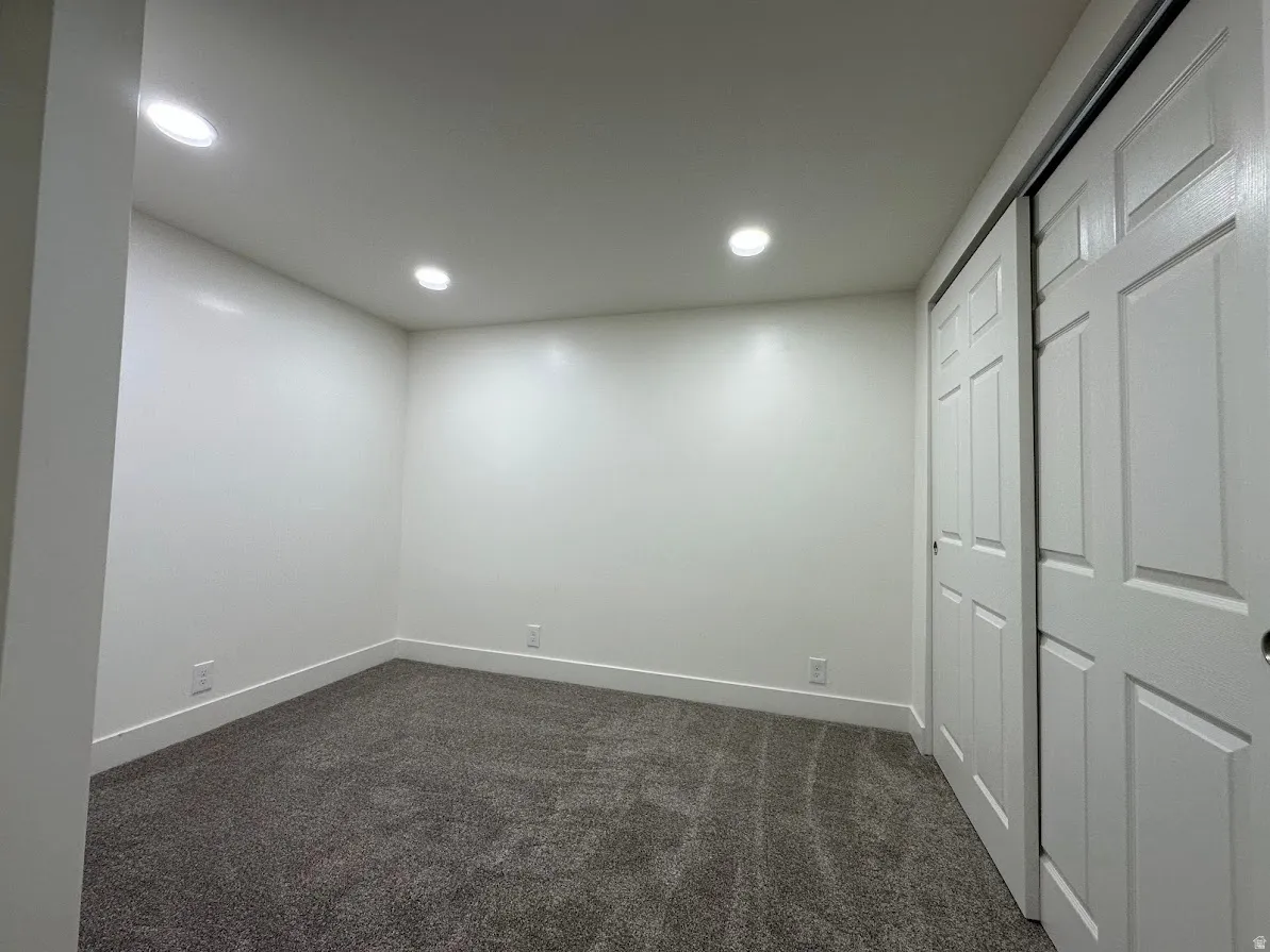 Recessed lighting, white walls, gray carpeting, white trim, and a white sliding closet door