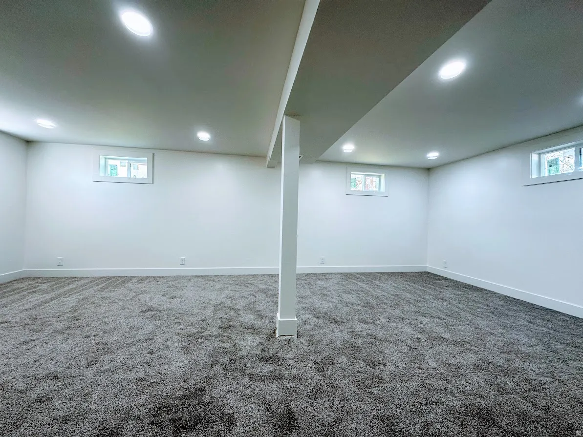 Spacious room with gray textured carpeting, white walls, and recessed lighting
