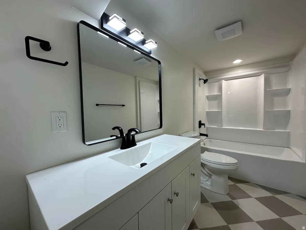 Bathroom featuring a white vanity with integrated sink, black framed mirror, three-light black fixture, and a white tub with shower surround