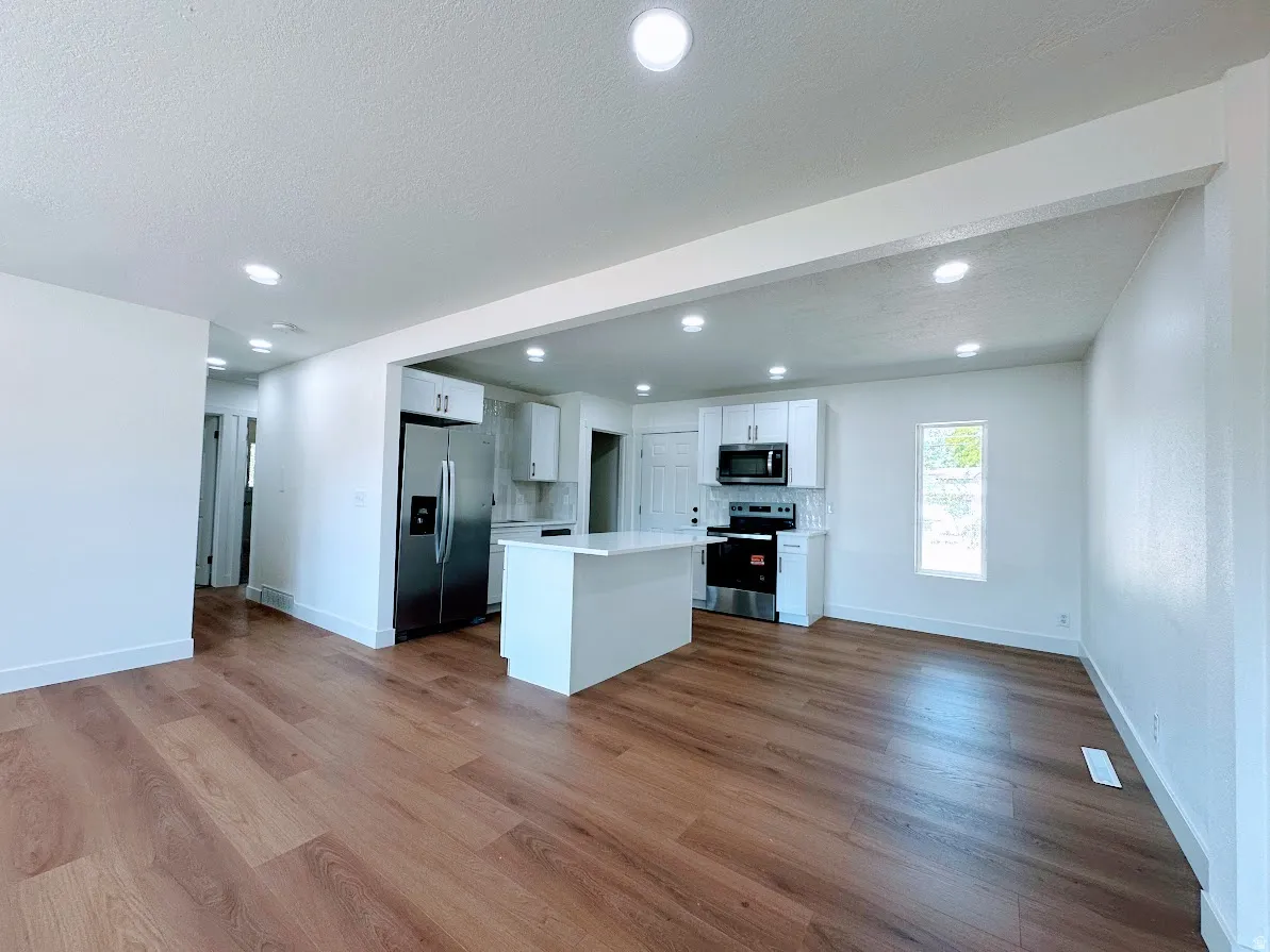 Open-concept living space featuring wood-finish flooring, recessed lighting, and a kitchen island