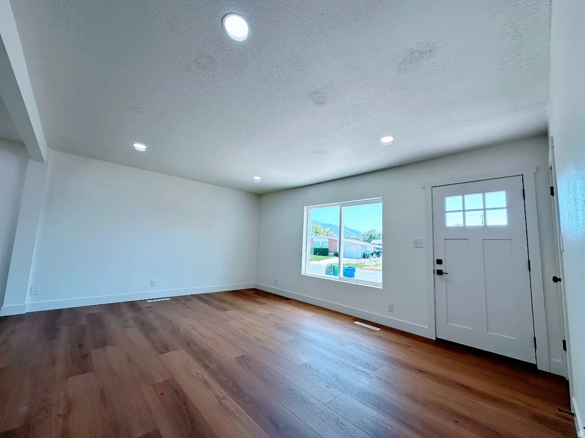 Wood-finish flooring, recessed lighting, white walls, and a front entry door with glass panels