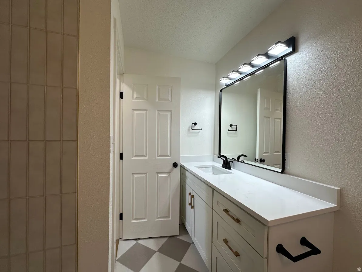 Vanity with white countertop, integrated sink, and bronze hardware