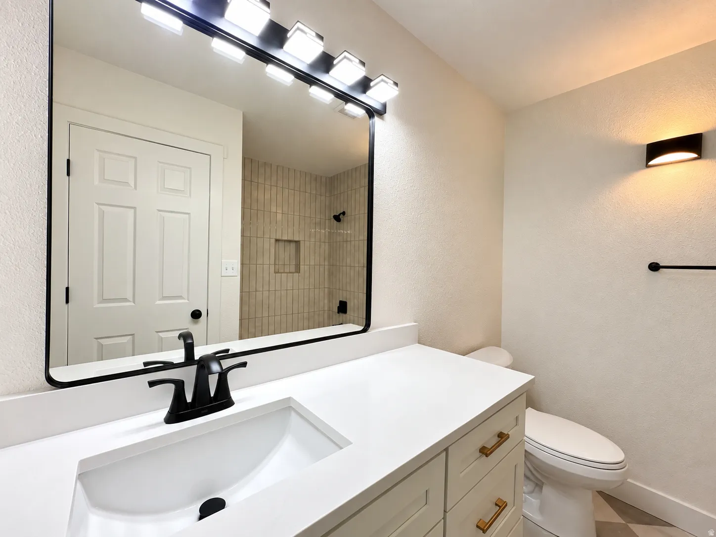 White vanity with gold-tone hardware, integrated rectangular sink, and matte black faucet