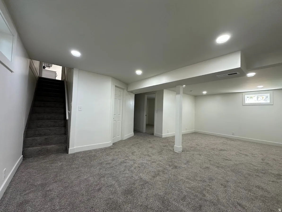 Expansive carpeted area featuring recessed lighting, a built-in staircase, and a window