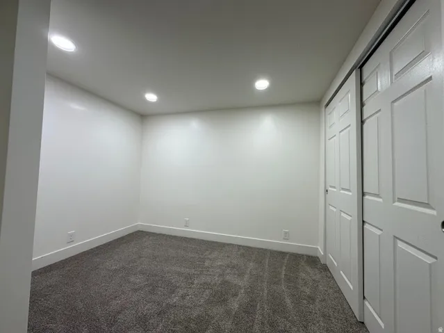 Recessed lighting, white walls, gray carpeting, white trim, and a white sliding closet door