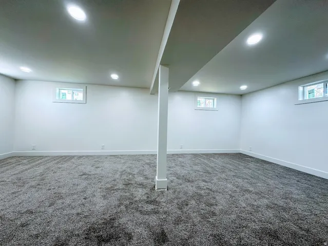 Spacious room with gray textured carpeting, white walls, and recessed lighting