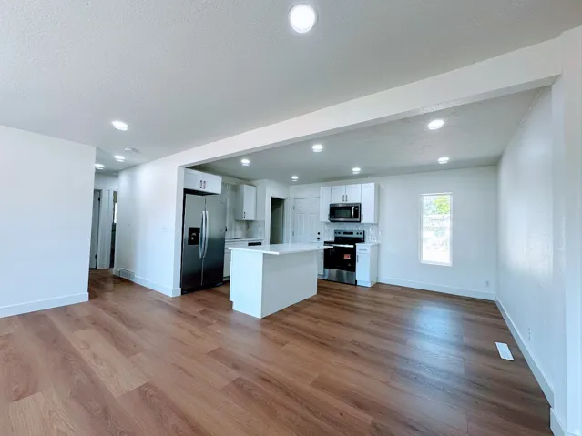 Open-concept living space featuring wood-finish flooring, recessed lighting, and a kitchen island