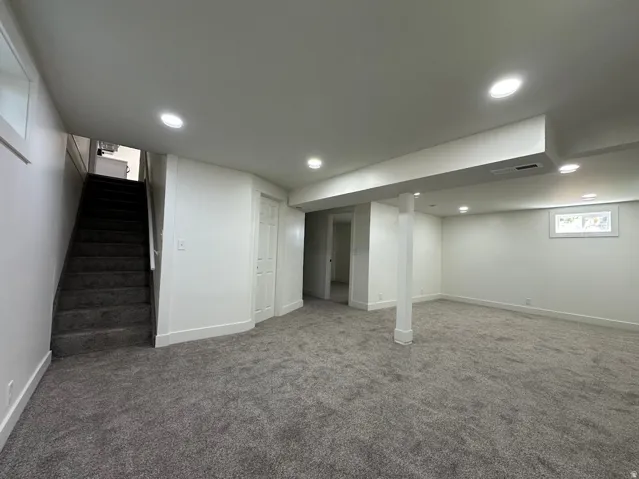 Expansive carpeted area featuring recessed lighting, a built-in staircase, and a window