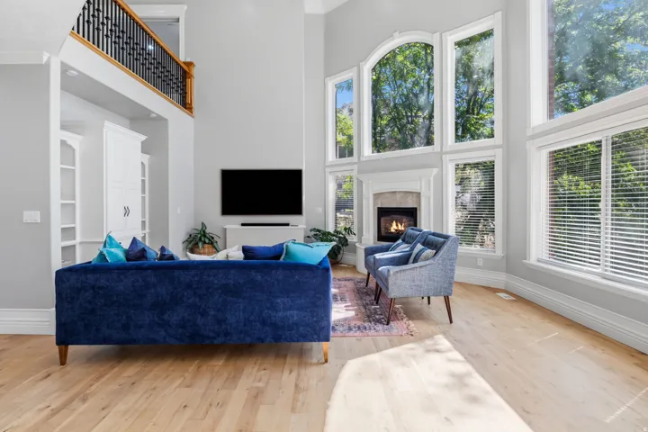 Hardwood flooring, soaring ceilings, fireplace with stone surround, custom built-in cabinetry, and a balcony overlook