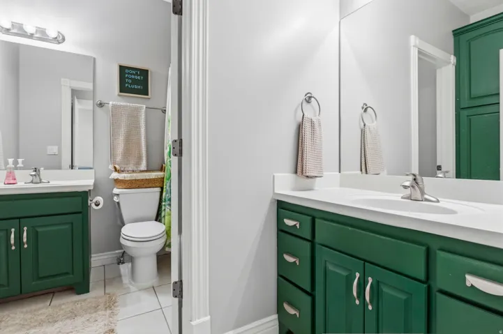 Dual vanity with green cabinetry, white countertops, and integrated sinks