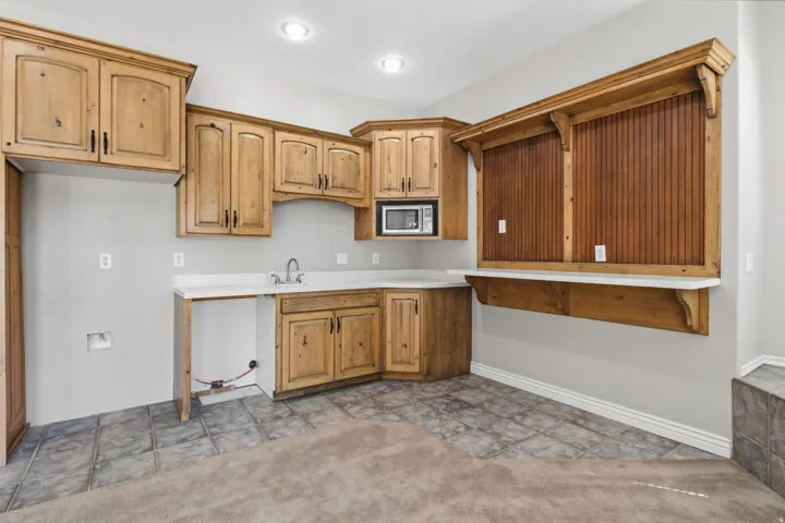 Wood-finish cabinetry with dark hardware, a built-in microwave, and a stainless steel sink