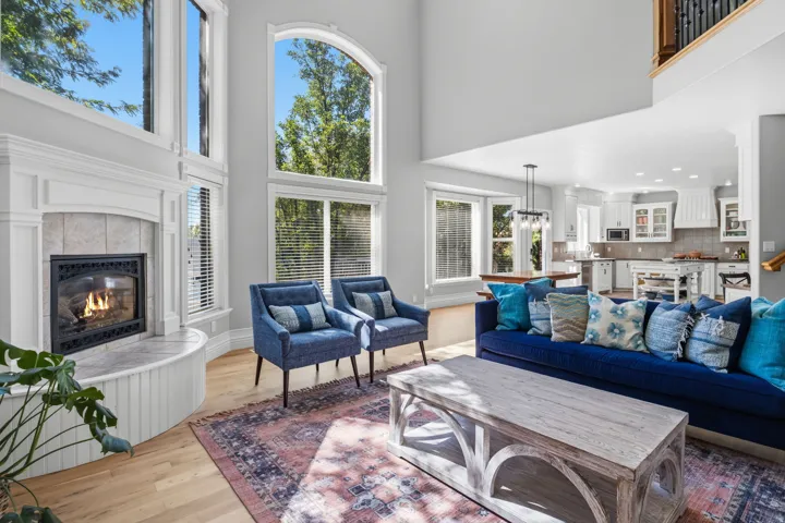 Vaulted ceiling, large windows, light wood-finish flooring, built-in fireplace, and an open-concept layout
