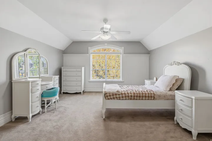Carpeted flooring, vaulted ceiling, built-in window with an arched transom, and wainscoting detail