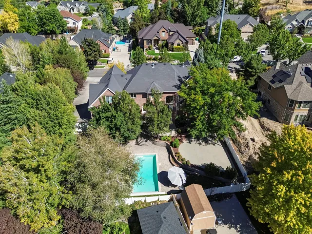 Brick exterior residence featuring a swimming pool, paved patio, and mature trees