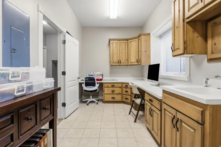 Built-in cabinetry with integrated desk space, solid surface countertops, and a utility sink