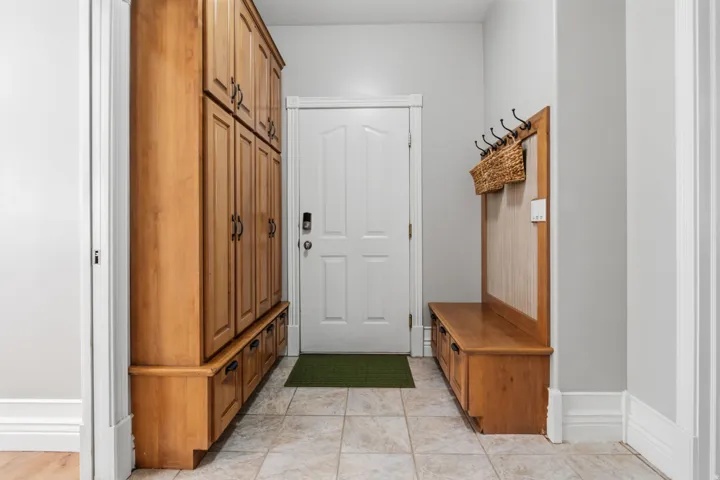 Built-in wood-finish cabinetry, tile flooring, and integrated coat rack with bench seating