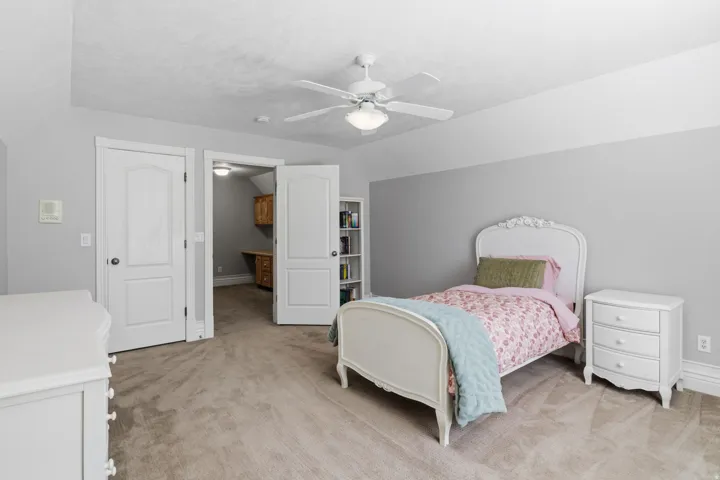 Wall-to-wall carpeting, recessed ceiling, ceiling fan with integrated lighting, two panel doors, and a built-in bookcase