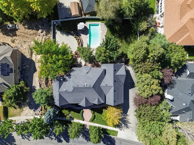 Asphalt shingle roofing, mature trees, and an inground swimming pool