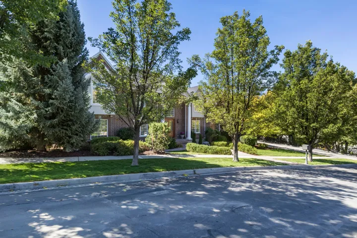 Brick and stucco exterior with multiple windows, mature landscaping, and a manicured lawn