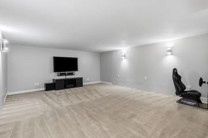 Spacious room with light gray walls, wall-mounted sconces, and neutral-toned carpeting