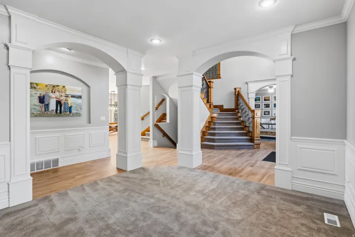 Dual arched entryways, extensive wainscoting, wood-finish flooring, staircase with carved wood handrail and wrought iron balusters, recessed lighting
