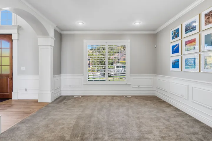 Formal living space featuring wainscoting, crown molding, arched entry, recessed lighting, and wood-finish flooring