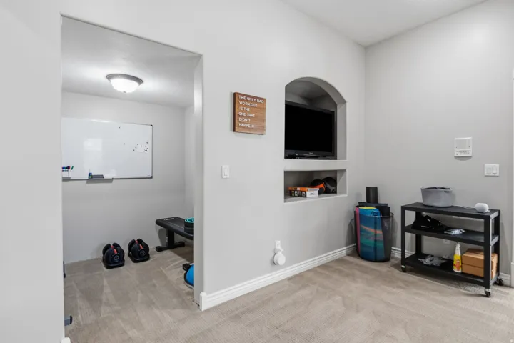 Carpeted flooring, recessed wall niche with built-in shelving, white baseboards, and a flush mount ceiling light fixture