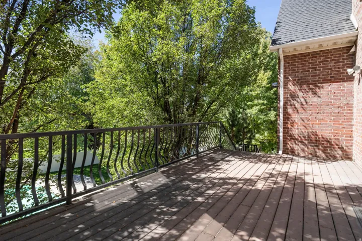 Expansive wood-finish deck with decorative wrought iron railing and brick exterior