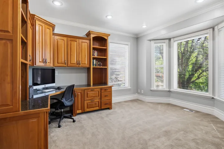 Built-in custom cabinetry with granite-finish countertops, recessed lighting, and bay windows with blinds