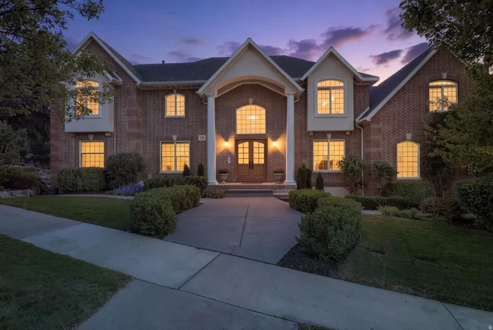 Brick exterior with multiple gabled rooflines, a covered entry porch with white columns, and a concrete paver walkway