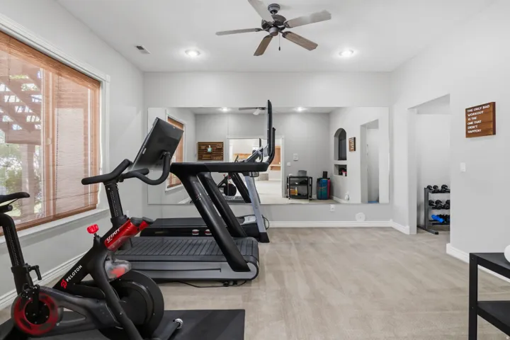 Recessed lighting, ceiling fan, mirrored wall, arched alcove, and neutral carpeting